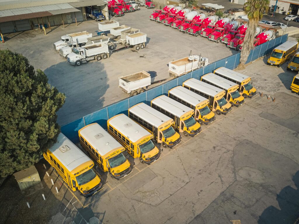 Aerial view of school buses and trucks parked in an industrial lot.